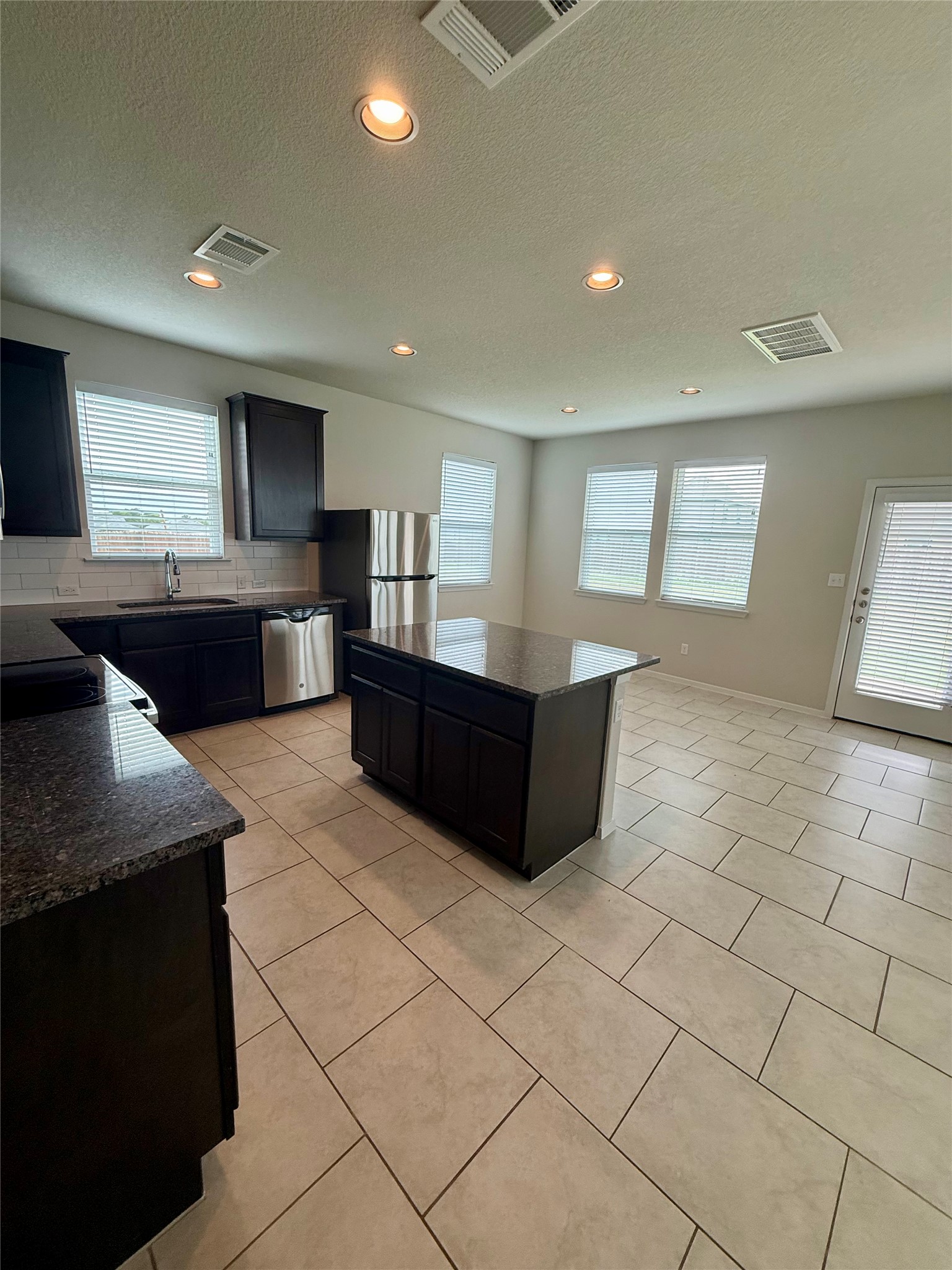 212 Lake Placid Run Elgin, TX 78621 - Photo 5 of 27 A well-appointed kitchen showcasing dark cabinetry, granite countertops, and modern stainless steel appliances.