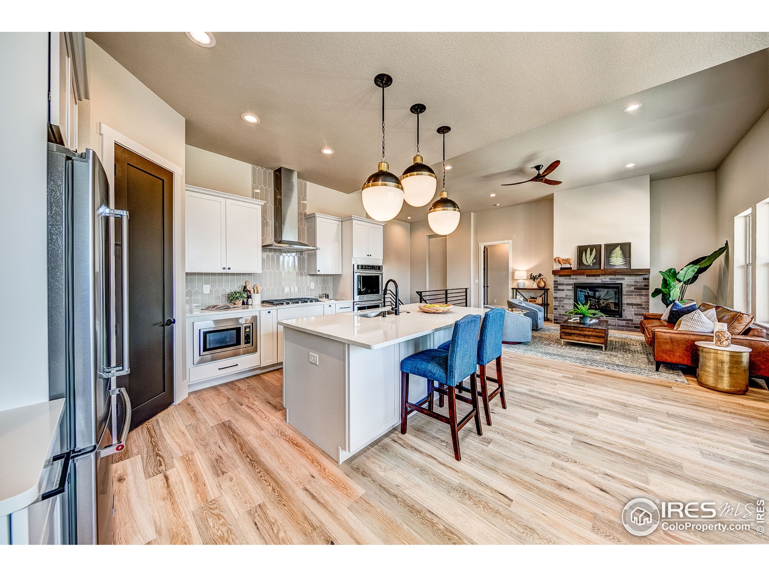 a open kitchen view with stainless steel appliances granite countertop a refrigerator a stove a sink dishwasher and a dining table with wooden floor