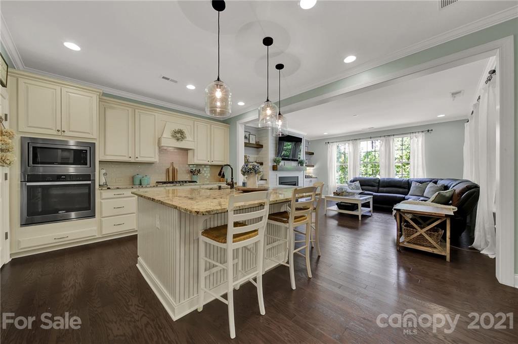 1033 Emory Lane Fort Mill, SC 29708 - Photo 12 of 48 a kitchen with stainless steel appliances kitchen island granite countertop a stove a sink a dining table and chairs with wooden floor