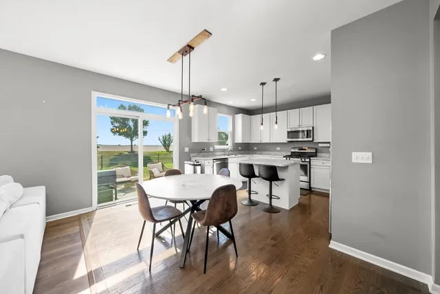 a kitchen with stainless steel appliances granite countertop a refrigerator a sink dishwasher a stove and white cabinets with wooden floor