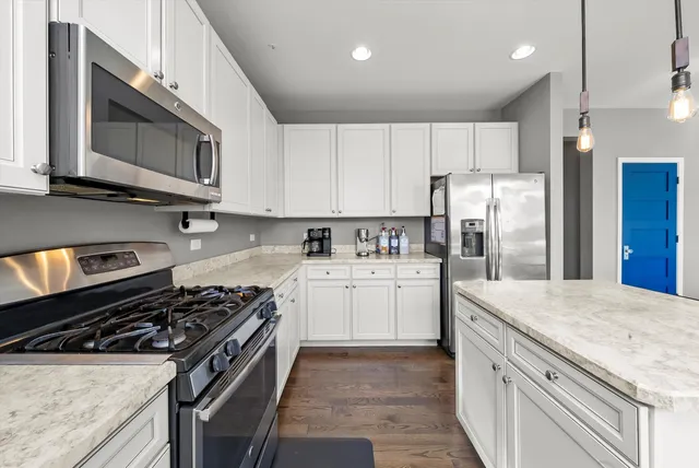 a kitchen with a sink stove and white cabinets with wooden floor