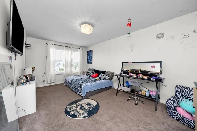 a bedroom with a bed a flat screen tv and a window