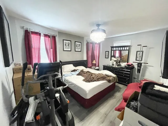 a bedroom with bed a flat tv screen and a dresser
