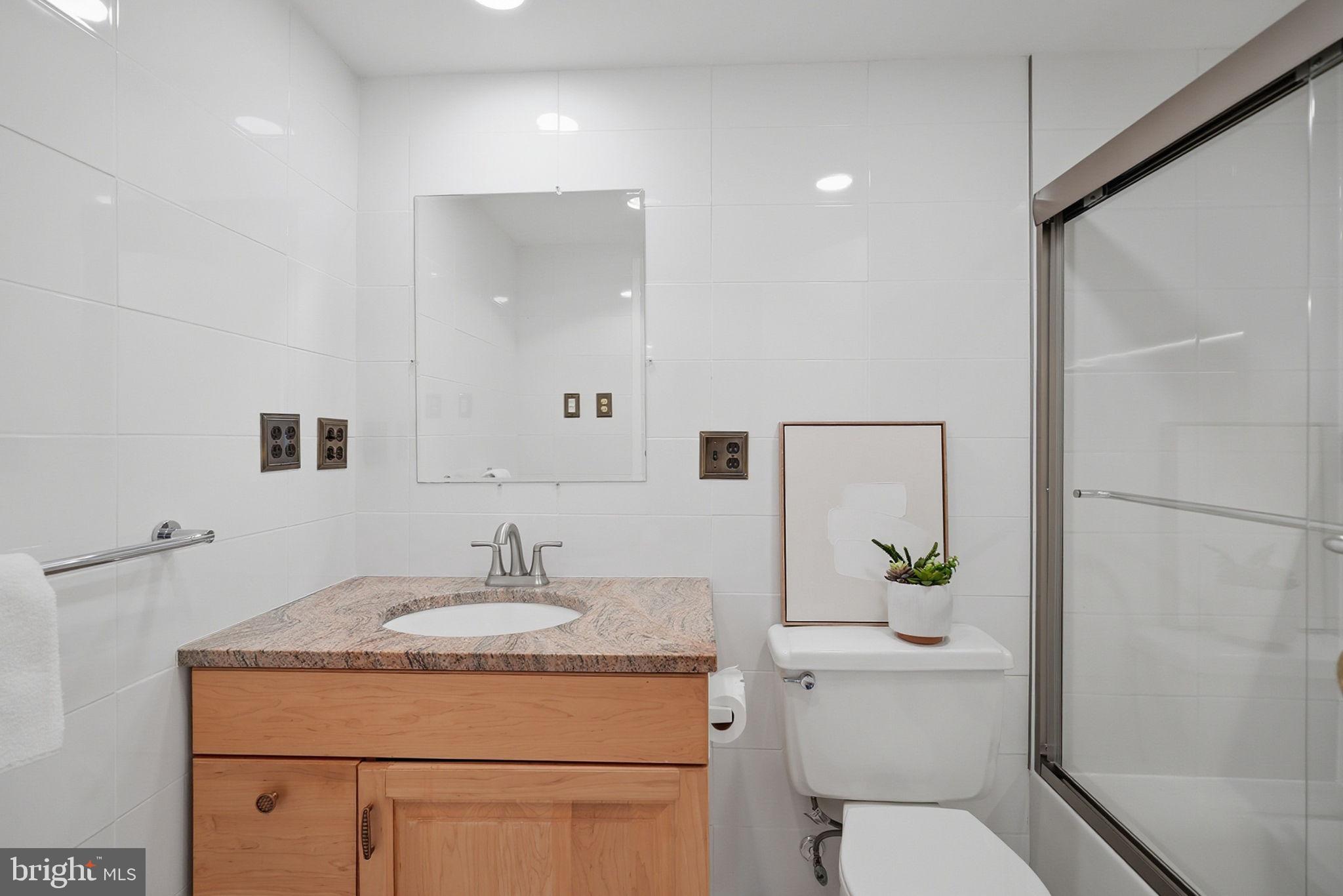 3001 Veazey Street Northwest, Unit 116 Washington, DC 20008 - Photo 23 of 40 a bathroom with a granite countertop sink toilet and a mirror