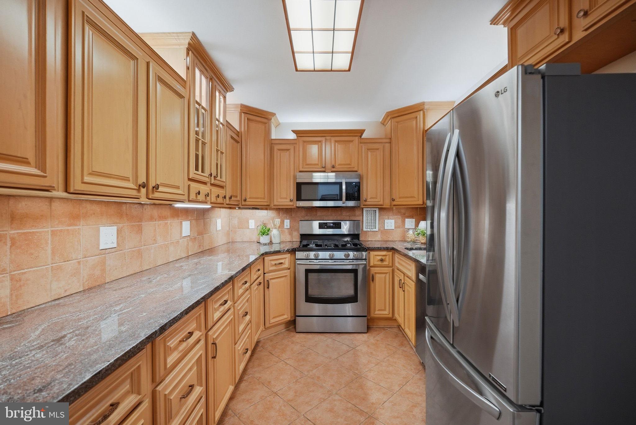 3001 Veazey Street Northwest, Unit 116 Washington, DC 20008 - Photo 10 of 40 a kitchen with stainless steel appliances granite countertop a refrigerator and a stove top oven