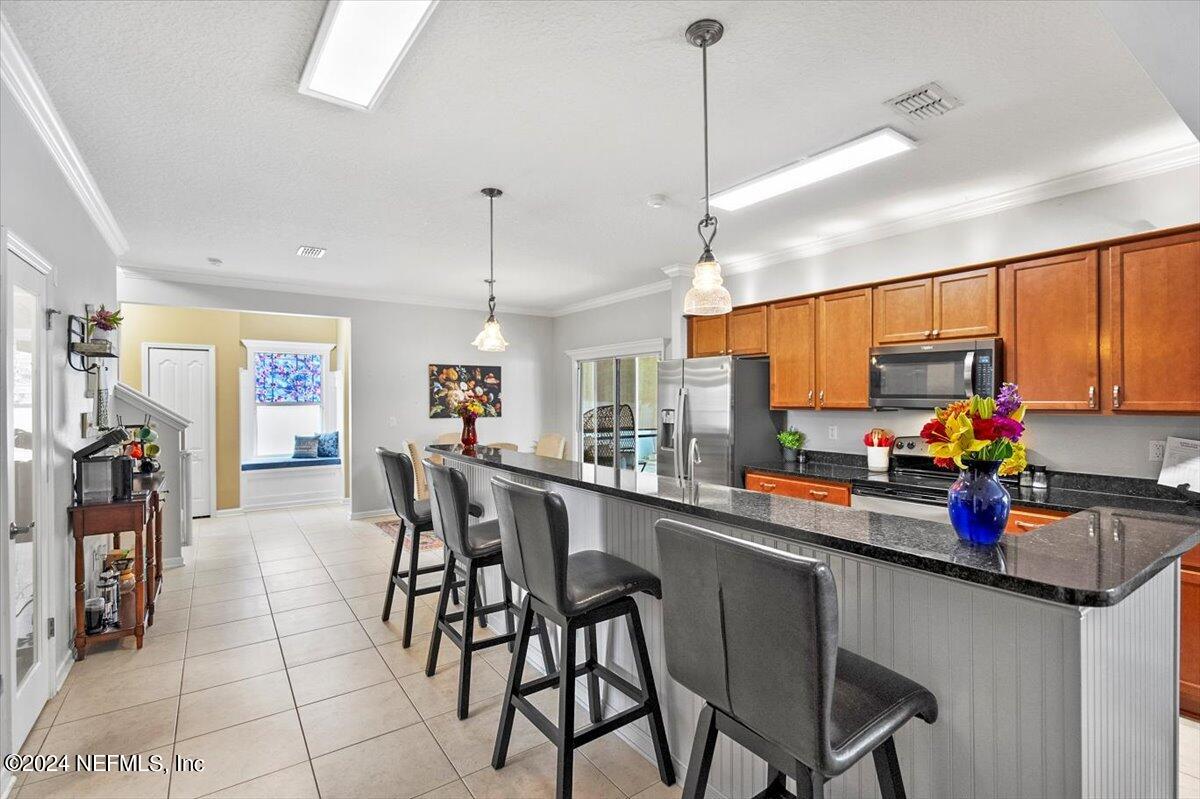 16402 Tisons Bluff Road Jacksonville, FL 32218 - Photo 11 of 45 a kitchen with stainless steel appliances kitchen island granite countertop a table chairs and a refrigerator