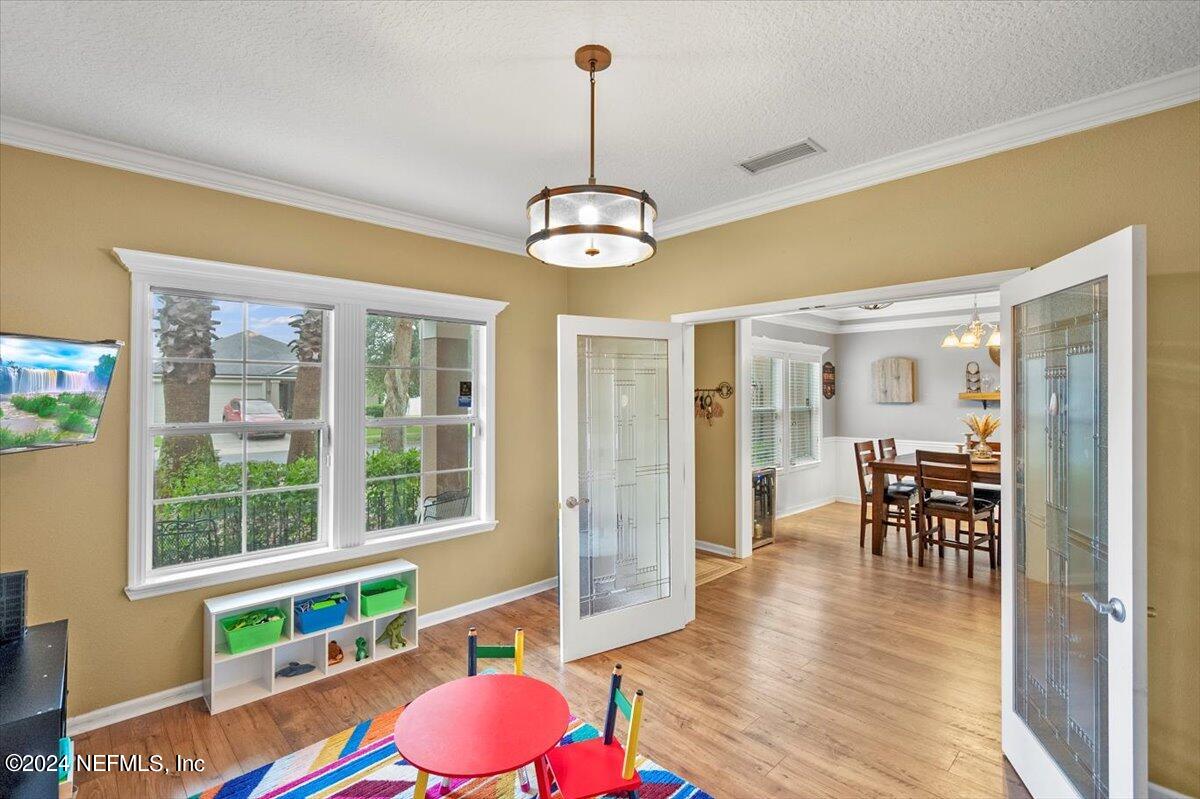 16402 Tisons Bluff Road Jacksonville, FL 32218 - Photo 6 of 45 a dining room with wooden floor a chandelier a wooden table and chairs