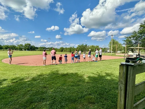 a group of people standing around in a yard with large trees
