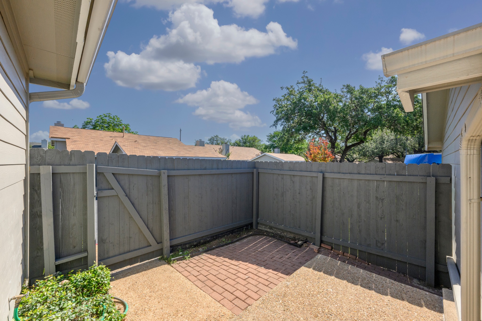 6501 Brush Country Road, Unit 120 Austin, TX 78749 - Photo 22 of 26 Private outdoor courtyard featuring a wood privacy fence, a brick paver patio, and gravel surfacing