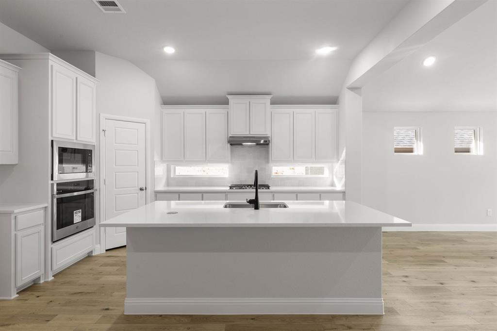 14422 Mietner Street Pilot Point, TX 76258 - Photo 6 of 23 a kitchen with kitchen island white cabinets and stainless steel appliances