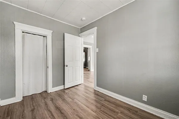 a view of an empty room with wooden floor and closet