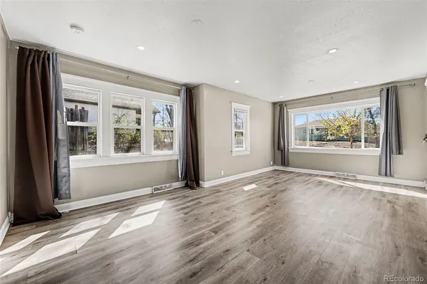 a view of an empty room with a window and wooden floor
