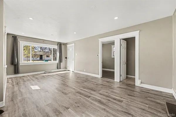 an empty room with wooden floor cabinet and windows