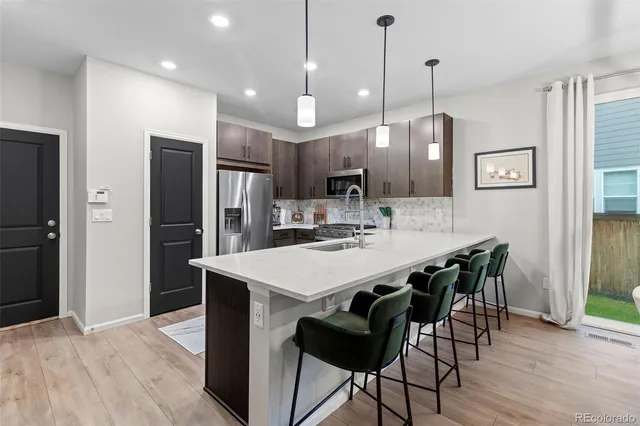 a kitchen with stainless steel appliances kitchen island granite countertop a dining table chairs and refrigerator
