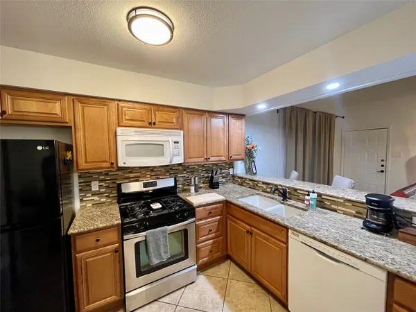 a kitchen with granite countertop a sink stainless steel appliances and cabinets