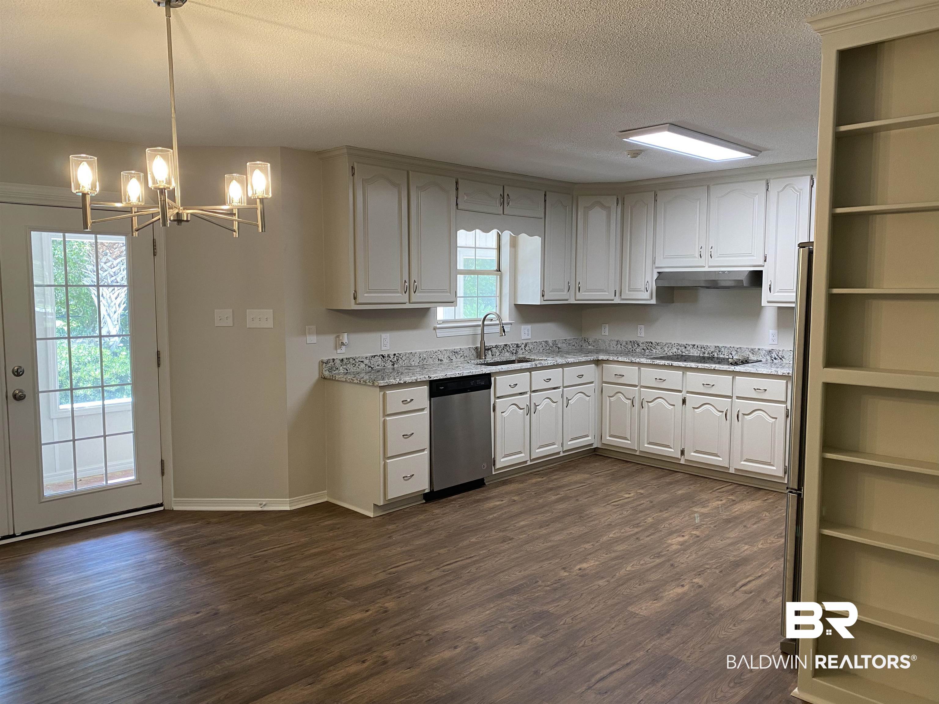 12150 Lee Bishop Road Irvington, AL 36544 - Photo 9 of 26 Kitchen featuring stainless steel dishwasher, dark wood-type flooring, a textured ceiling, a sink, and a notable chandelier