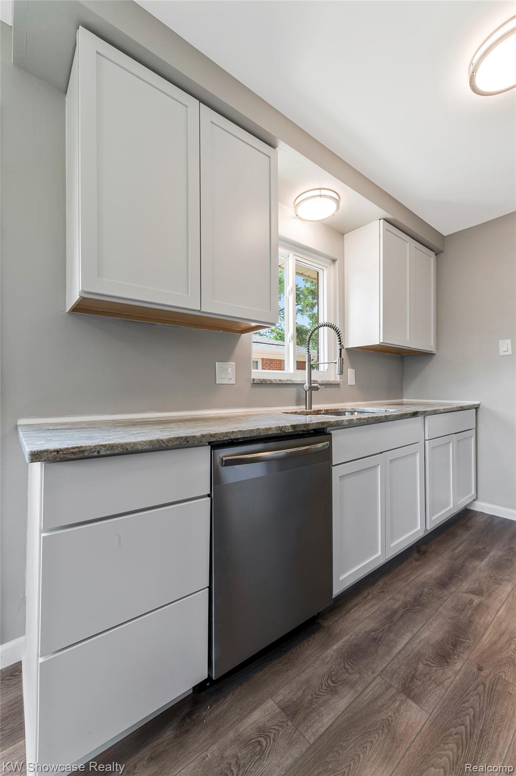 8936 Merriman Road Livonia, MI 48150 - Photo 27 of 49 Contemporary kitchen featuring light gray cabinetry, stone-finish countertops, stainless steel dishwasher, and wood-look flooring