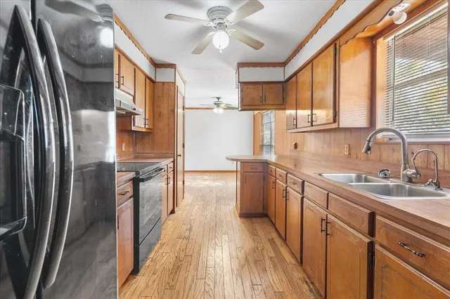 a kitchen with stainless steel appliances granite countertop a refrigerator a sink dishwasher a stove and white countertops with wooden floor