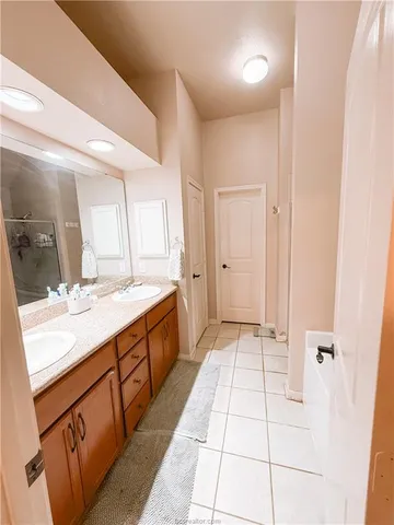 a spacious bathroom with a double vanity sink a mirror and a shower