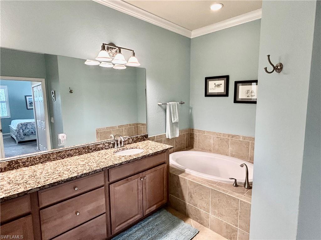 9511 Napoli Lane, Unit 202 Naples, FL 34113 - Photo 28 of 50 a bathroom with a granite countertop bathtub a sink and a mirror