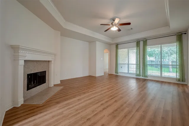 a view of an empty room with wooden floor fireplace and a window