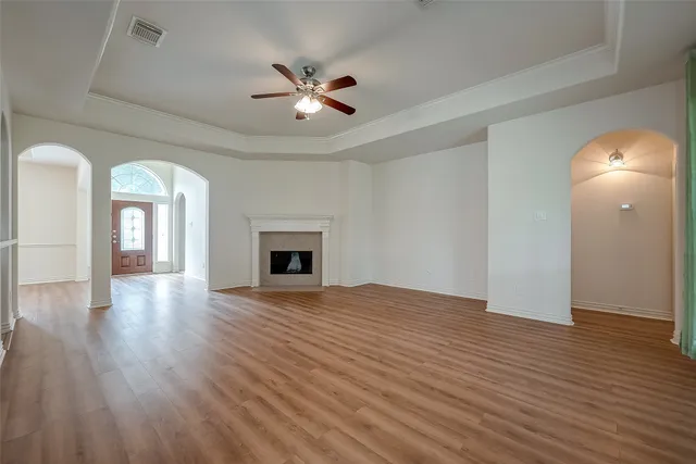 a view of an empty room with wooden floor and a fireplace