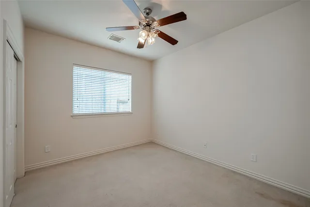 an empty room with a chandelier fan and windows