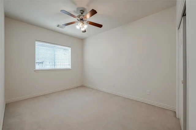 an empty room with a chandelier fan and windows
