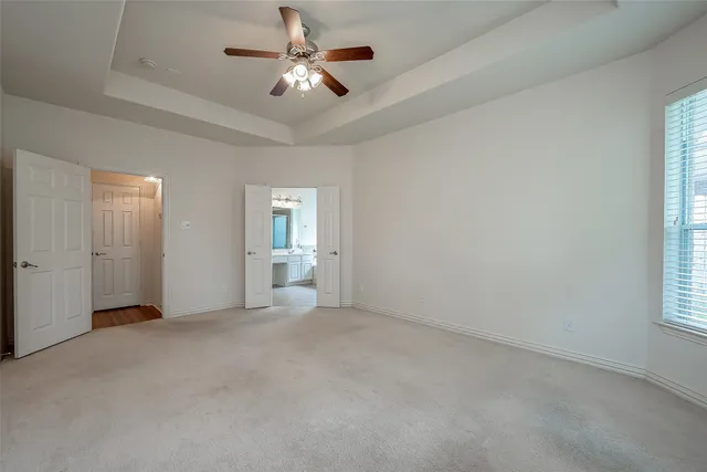 an empty room with chandelier fan and windows
