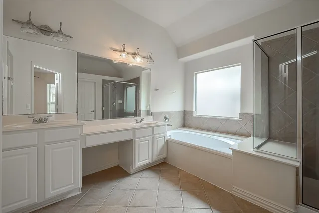 a bathroom with a tub sink shower and two mirror