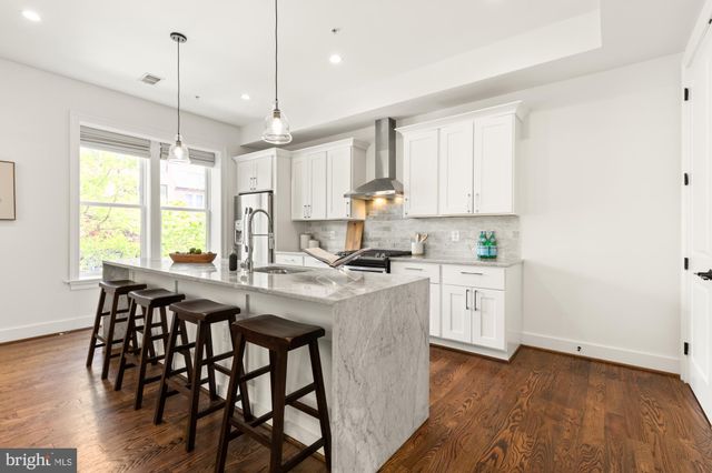 a kitchen with stainless steel appliances granite countertop white cabinets a sink stove and white appliances