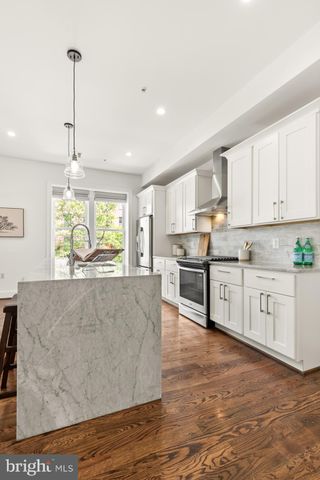 a large kitchen with stainless steel appliances granite countertop a stove a sink and white cabinets with wooden floor