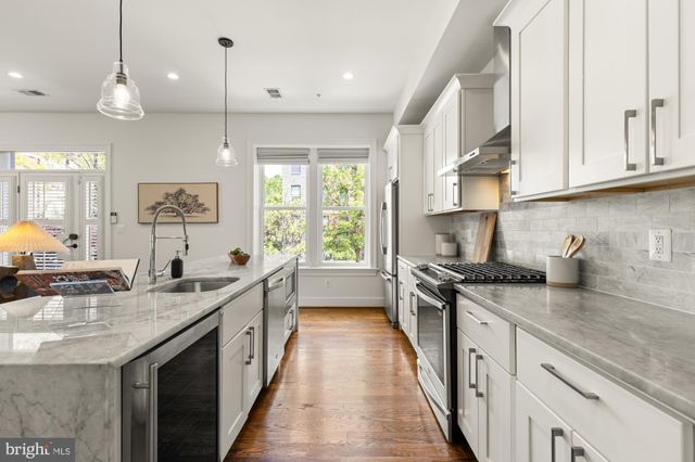 a kitchen with stainless steel appliances granite countertop a sink a stove and a wooden floors