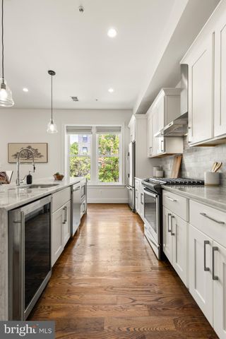 a large kitchen with stainless steel appliances kitchen island granite countertop a stove a sink and white cabinets