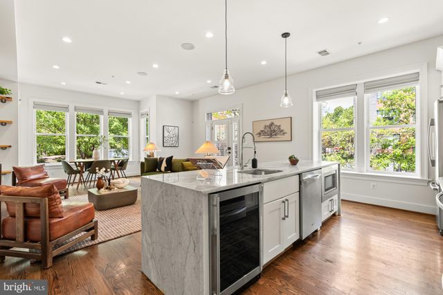 a large kitchen with stainless steel appliances a stove a sink dishwasher and a large refrigerator with wooden floor