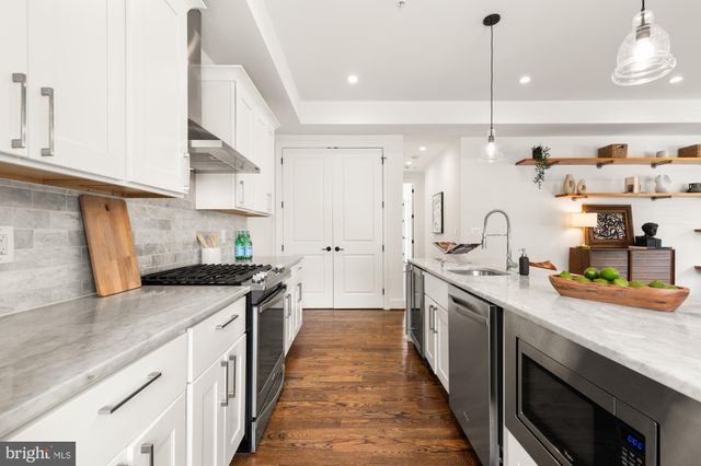 a kitchen with stainless steel appliances granite countertop a sink a stove and a wooden floors