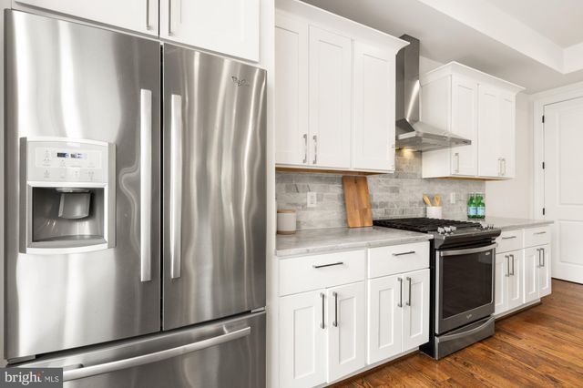 a kitchen with stainless steel appliances white cabinets and wooden floors
