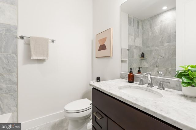 a bathroom with a granite countertop sink a toilet and a mirror