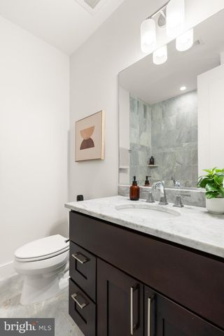 a bathroom with a granite countertop sink a toilet and a mirror