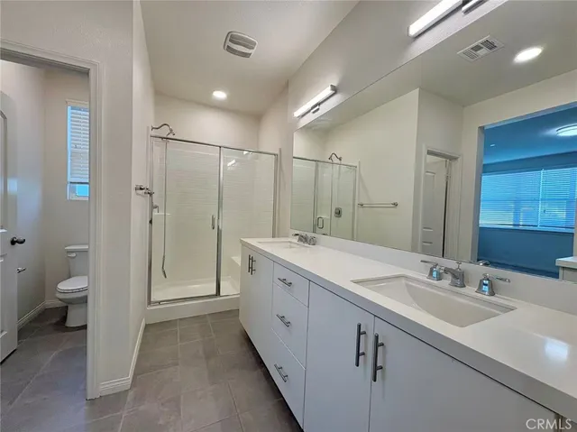 a spacious bathroom with a double vanity sink toilet and shower