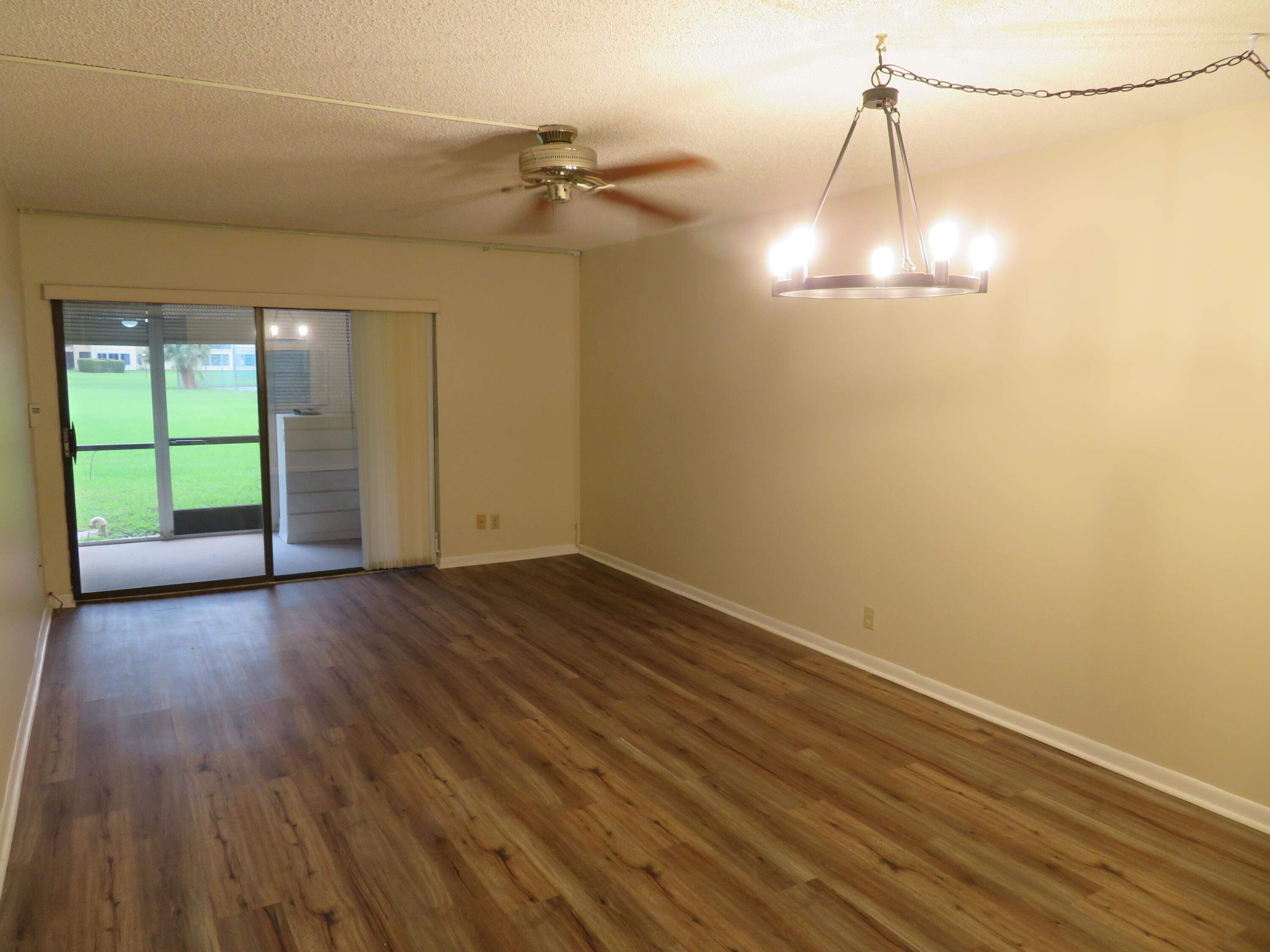 9233 Southwest 8th Street, Unit 117 Boca Raton, FL 33428 - Photo 28 of 37 an empty room with wooden floor fan and windows