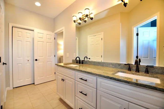 a spacious bathroom with a granite countertop sink a mirror and a shower