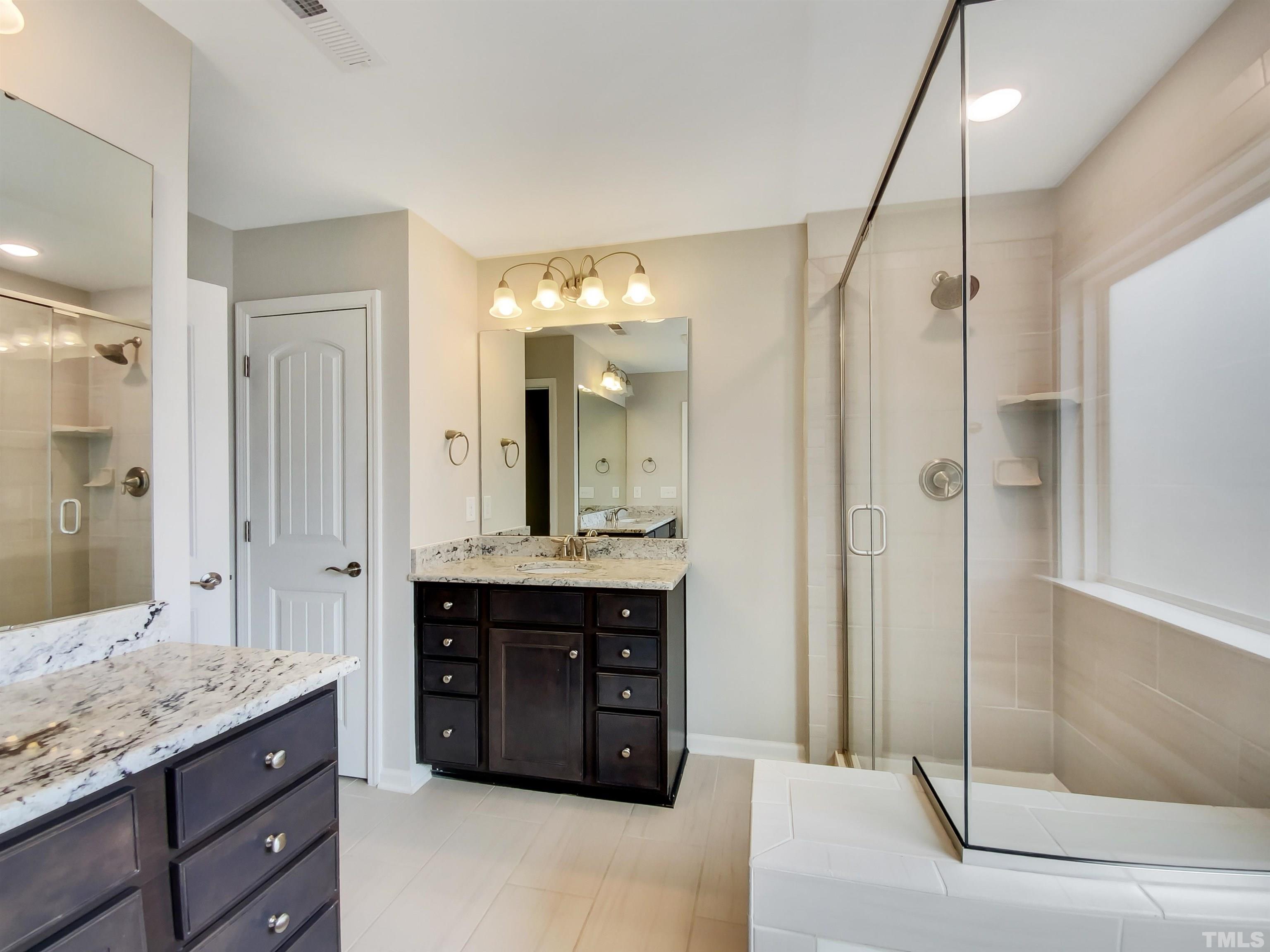 7006 Reedybrook Crossing Apex, NC 27523 - Photo 13 of 18 a spacious bathroom with a granite countertop sink mirror and shower