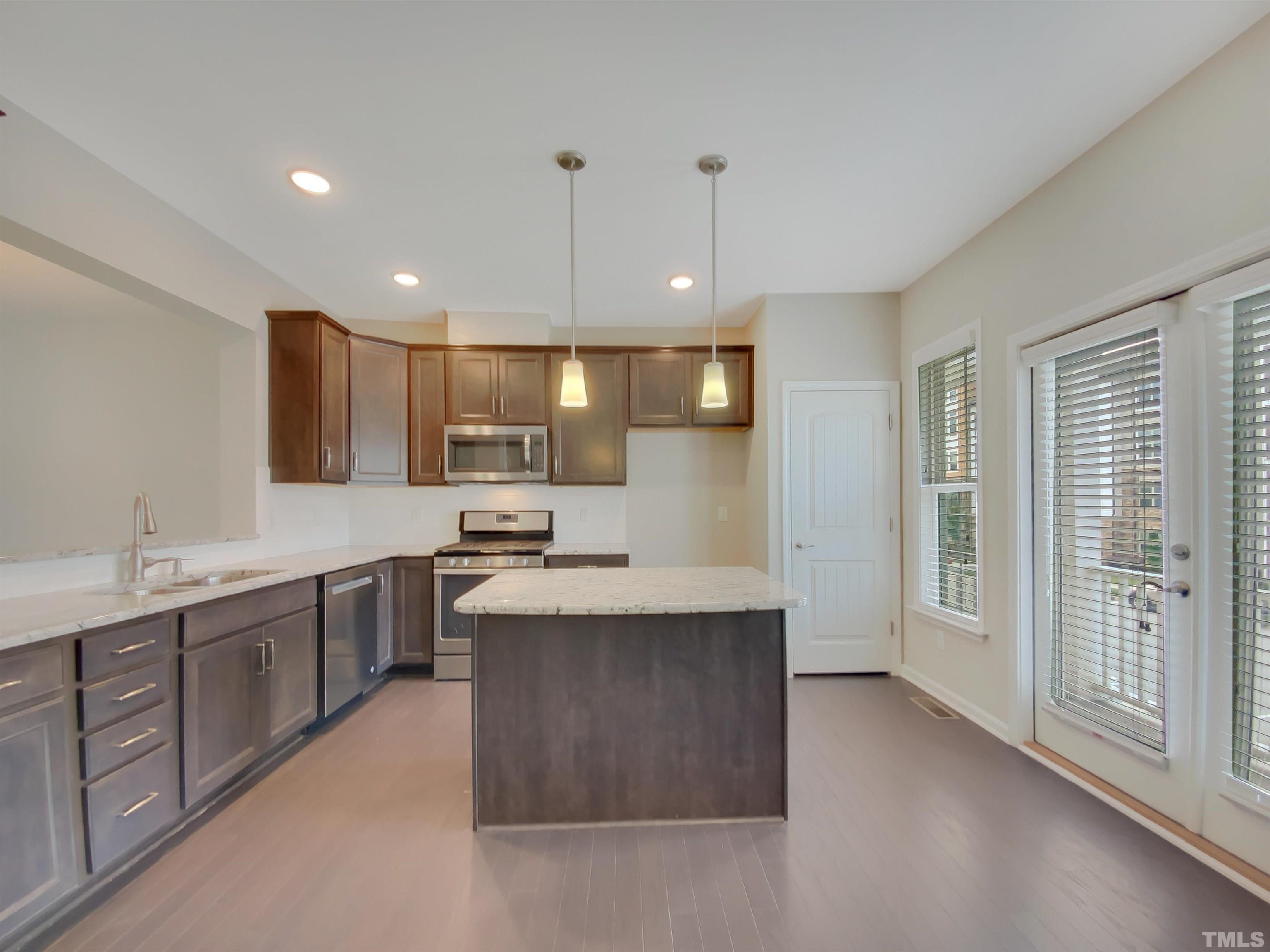 7006 Reedybrook Crossing Apex, NC 27523 - Photo 4 of 18 a kitchen with stainless steel appliances granite countertop a sink a stove and a refrigerator