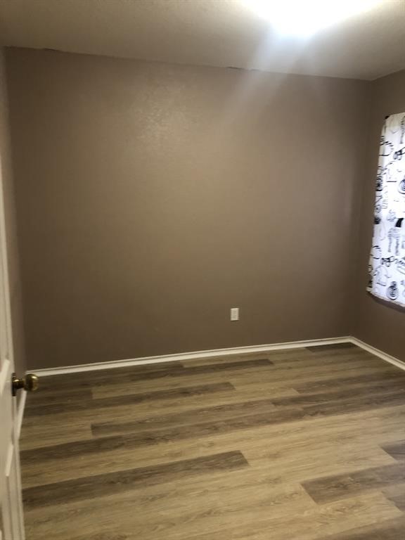 211 Woodley Road Leander, TX 78641 - Photo 11 of 15 Smooth walls and classic wood-look flooring establish a clean base in this versatile bedroom.