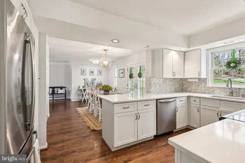 a kitchen with white cabinets and wooden floor