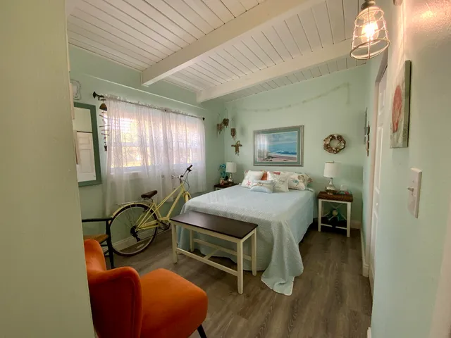 a bedroom with a bed and a chair with the wooden floor