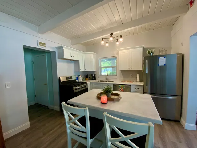 a kitchen with a dining table chairs refrigerator and microwave