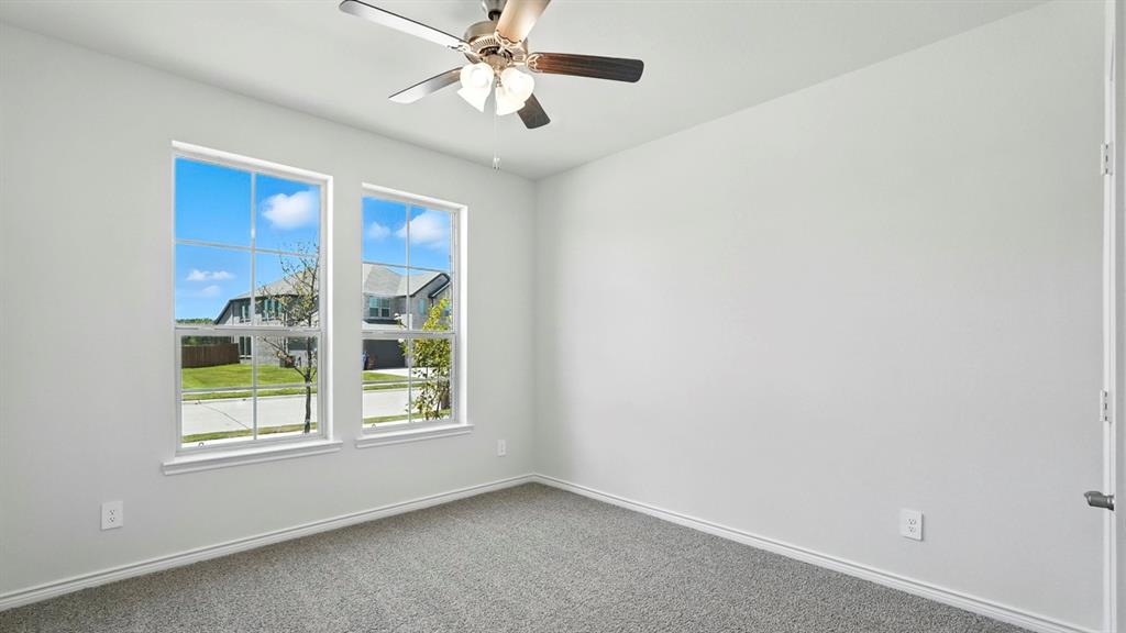 4191 Waldron Trail Forney, TX 75126 - Photo 19 of 20 Bright interior room featuring two large windows, gray carpet, white baseboards, and a ceiling fan with integrated lighting