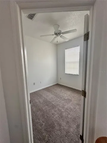 an empty room with a window and a fan